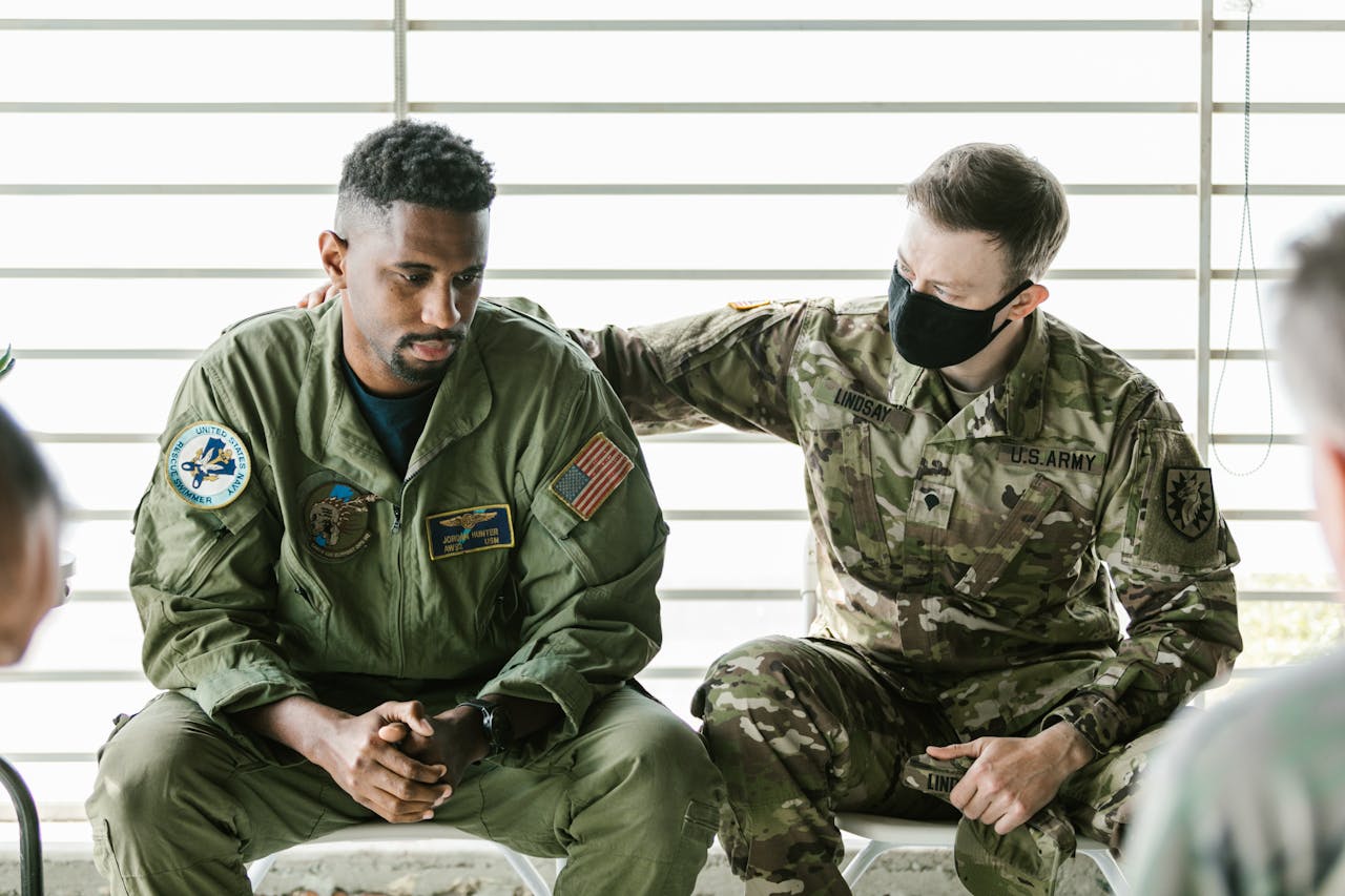 Two military personnel engaged in an emotional support session indoors.